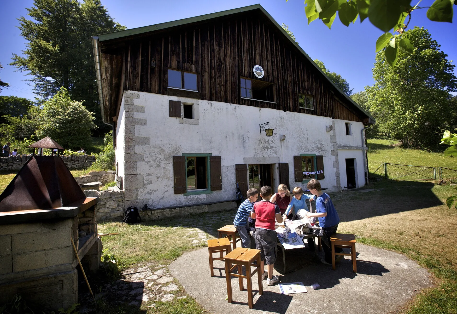 eine Gruppe von Menschen, die um einen Tisch vor einem Haus sitzen