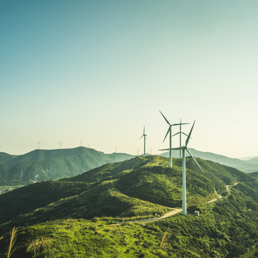 Photo of a group of turbines on lush green mountains Sistem de întreținere a instalațiilor fotovoltaice