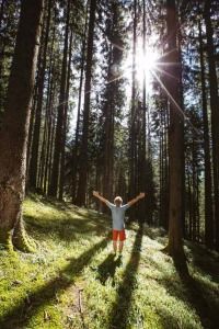 Ein Mann mit beiden Händen ausgestreckt in mitten eines Waldes