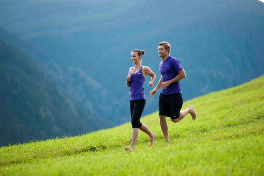 Ein Mann und eine Frau beim Laufen auf dem grünen Feld in den Bergen