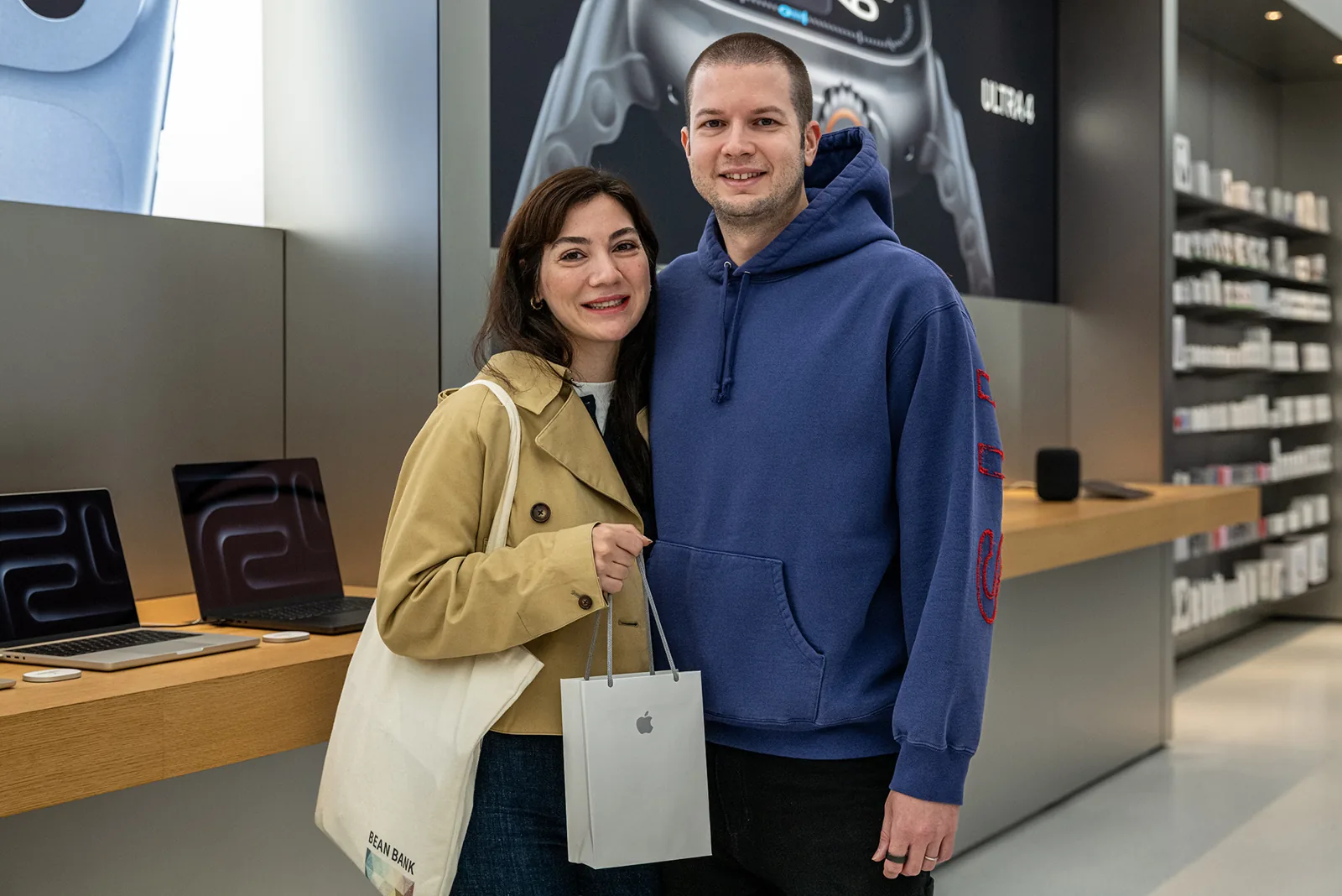 Koral Oral, Apple Zorlu mağazasında yanında bir kişiyle ve Apple alışveriş çantasıyla
