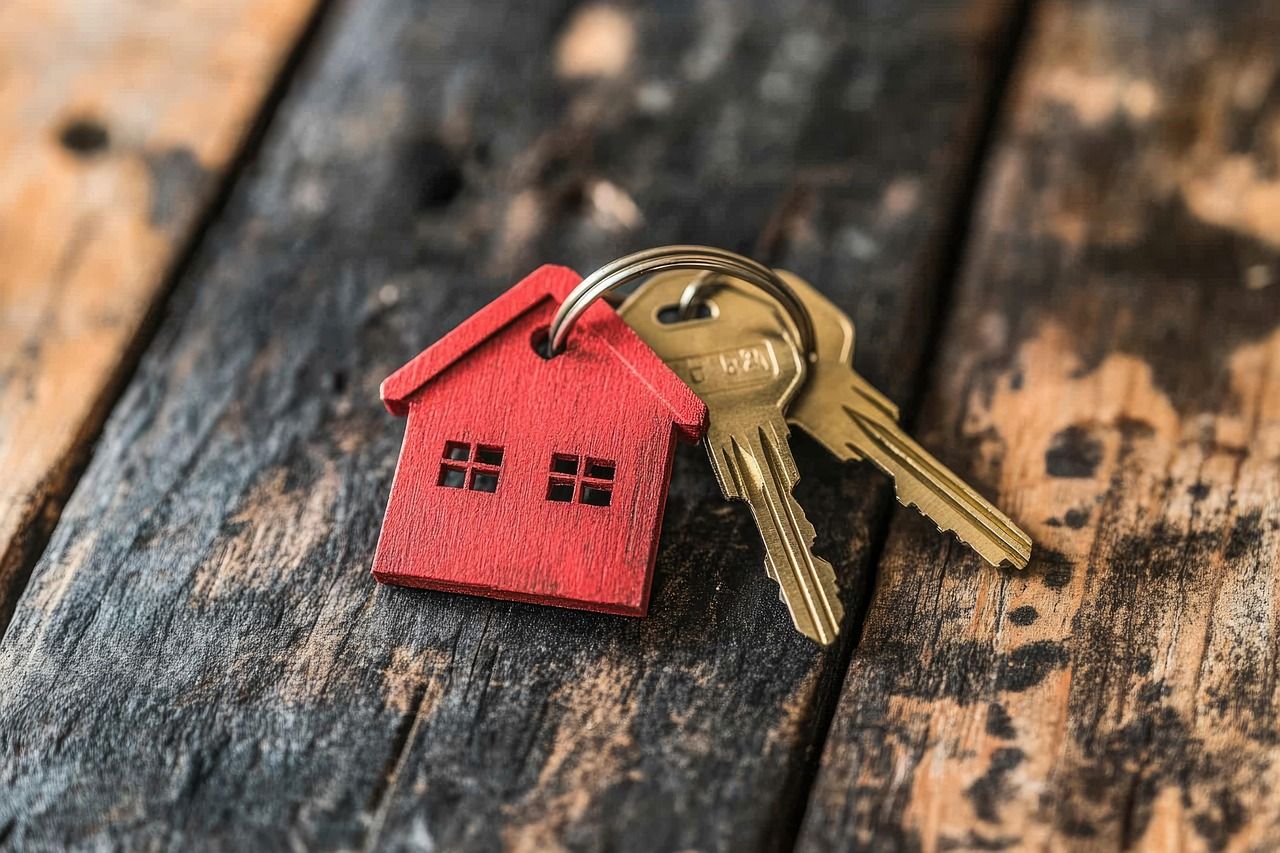 een sleutelhanger met daaraan een huisje en twee sleutels